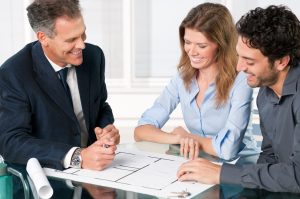 Happy young couple discussing with an estate agent about their new house plans